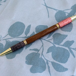 Un stylo à bille bicolore pour étudiant ou enseignant avec un corps tourné à la main en chêne des marais, avec des raccords en or poli.