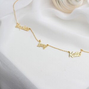 May include: Gold necklace with three names, "Sophia", "Lucy", and "Katie", spelled out in cursive.
