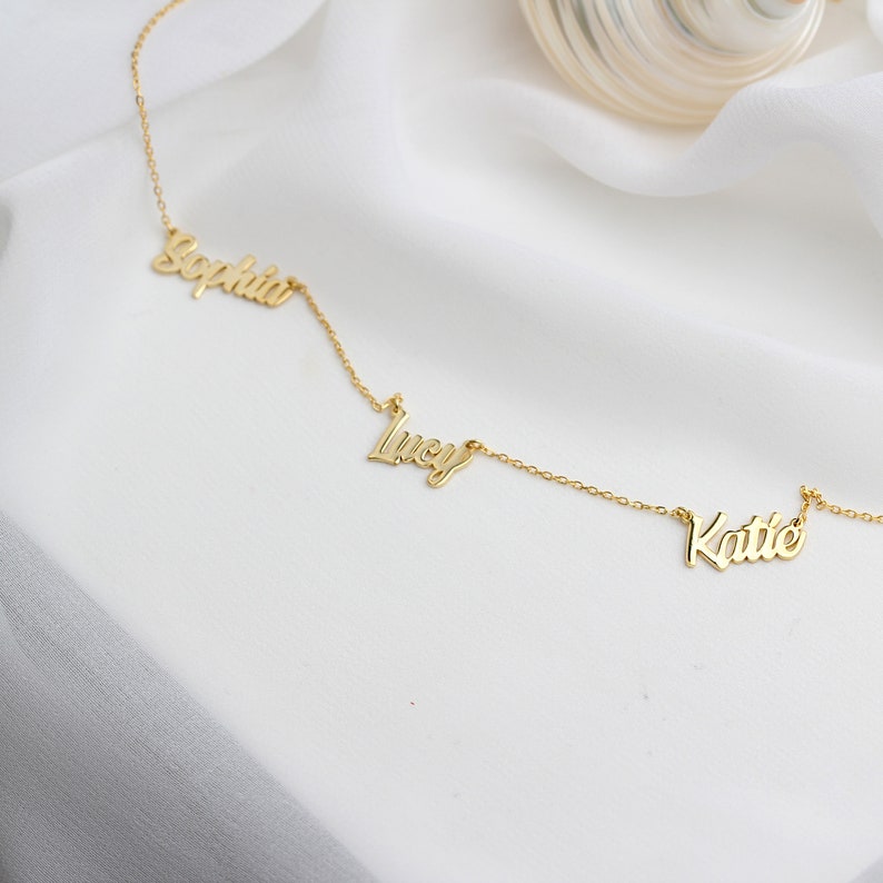 May include: Gold necklace with three names, "Sophia", "Lucy", and "Katie", spelled out in cursive.