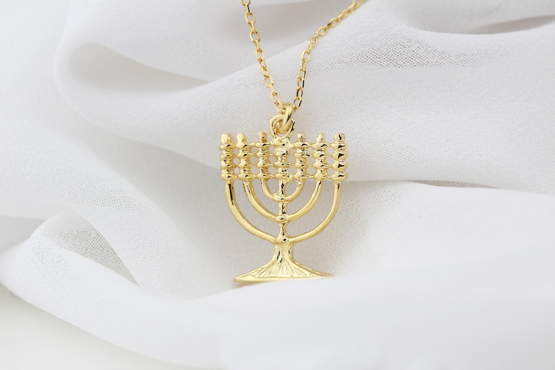 May include: A gold necklace with a menorah pendant. The menorah is a traditional Jewish symbol of light.