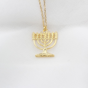 May include: A gold-toned necklace with a menorah pendant. The menorah is a traditional Jewish symbol.