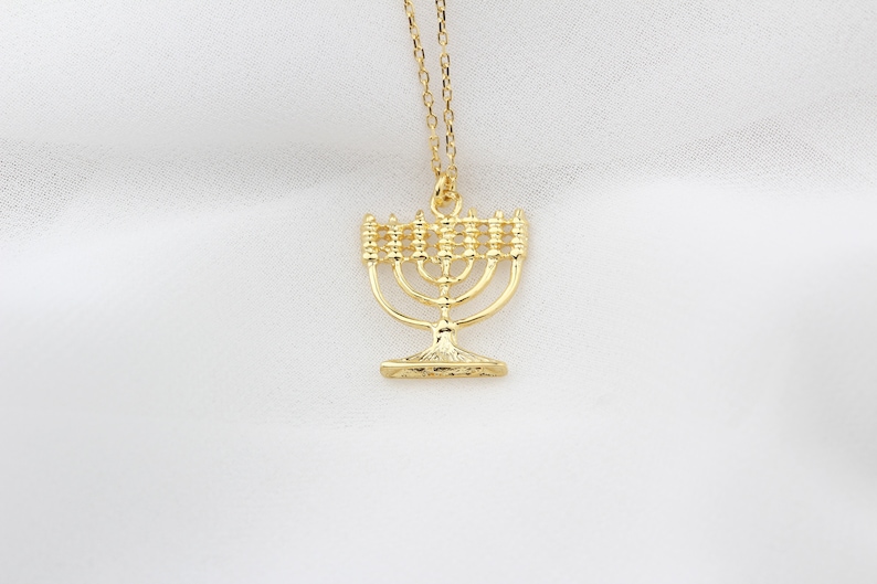 May include: A gold-toned necklace with a menorah pendant. The menorah is a traditional Jewish symbol.