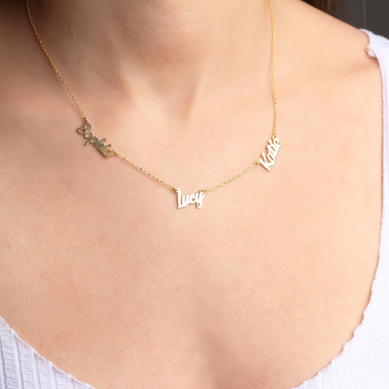 May include: A gold chain necklace with three names on it: 'Sophia', 'Lucy', and 'Katie'.