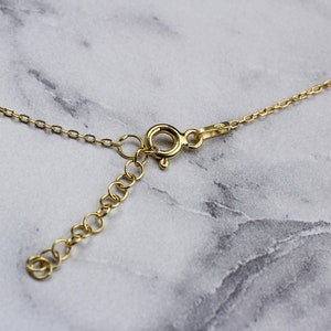 May include: A gold chain necklace with a lobster clasp closure. The chain is made of small, linked circles.
