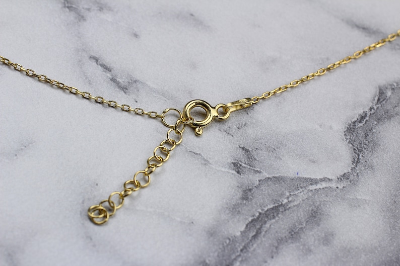 May include: A gold chain necklace with a lobster clasp closure. The chain is made of small, linked circles.
