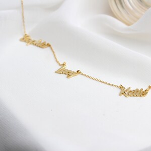 May include: A gold necklace with three names, "Sophia", "Lucy", and "Katie", spelled out in cursive.