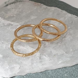 May include: Four gold-toned stacking rings with a hammered texture.