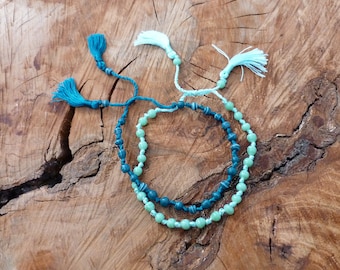 May include: Two beaded necklaces with turquoise and green beads and blue and white tassels.