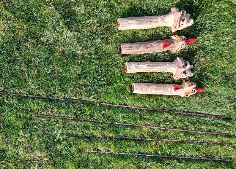 Op de afbeelding: Vier keramische kippenfiguren met rode kammen en keelzakken, staand op een groen gazon. De kippen zijn in lichtbruin geverfd en hebben gedetailleerde gezichtskenmerken.
