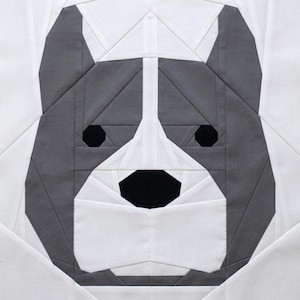 May include: A square fabric block featuring a geometric design of a dog's face. The dog's face is depicted in shades of gray and white, with black eyes and nose. The design is made up of various geometric shapes, creating a modern, artistic look.