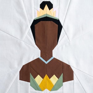 May include: A fabric art piece featuring a geometric design of a person wearing a crown. The figure is depicted with brown skin, black hair, and a light blue collar. The crown is yellow, black, and green. The background is white.