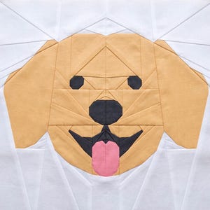 May include: A geometric quilt block featuring a dog's face. The dog has light brown fur, black eyes and nose, and a pink tongue. The background is white, and the design is made of fabric pieces sewn together.