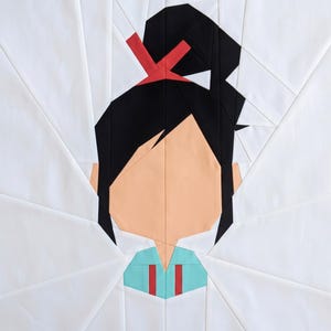 May include: A geometric quilt block featuring a stylized female face. The design uses black, peach, teal, and red fabric against a white background. The woman's hair is black, with a red hair accessory.