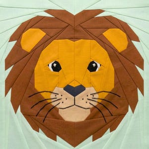 May include: A geometric patchwork lion face with a light green background. The lion's face is primarily yellow, with brown and orange accents for the mane and ears. The eyes are black with white highlights, and the nose is dark blue.