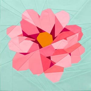 May include: A geometric quilt block featuring a stylized pink flower with an orange center. The flower is composed of various shades of pink fabric, set against a light teal background. The design is a modern take on a floral theme.