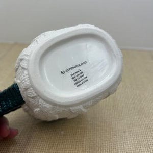 Pu&ograve; includere: Brocca in ceramica bianca con un design a maglia strutturato. Il manico &egrave; verde scuro. Il fondo della brocca riporta la scritta "by ANTHROPOLOGIE".