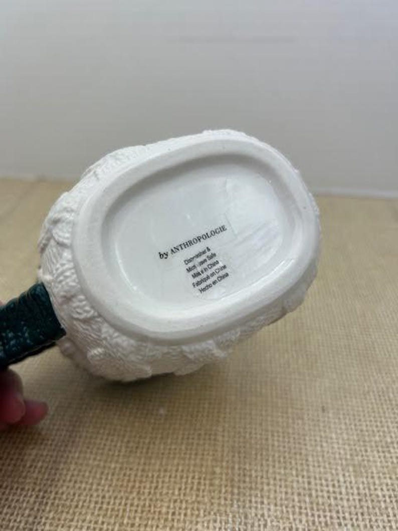 Pu&ograve; includere: Brocca in ceramica bianca con un design a maglia strutturato. Il manico &egrave; verde scuro. Il fondo della brocca riporta la scritta "by ANTHROPOLOGIE".