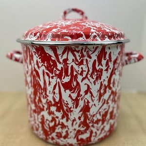 May include: A red and white enamelware pot with a lid. The pot has a marbled pattern and a silver rim. It features two side handles and a handle on the lid. The pot is approximately 8 inches in diameter and 7 inches tall.