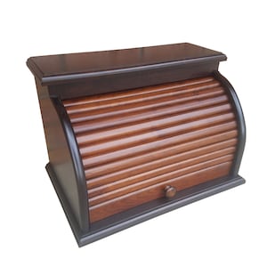 May include: A dark brown wooden bread box with a roll-top lid and a small drawer. The lid is made of wood slats and has a rounded shape.