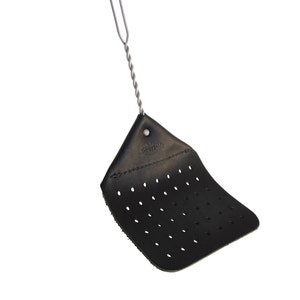 May include: A black leather fly swatter with a wire handle. The swatter has a grid of holes and the text "Golden's Fly Swatter" is embossed on the top.