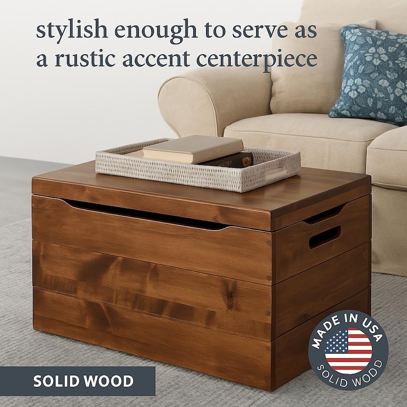 May include: A solid wood storage chest with a rich brown finish. The chest has a rectangular shape with a flat top and integrated handles. A woven tray with books sits on top. The text "stylish enough to serve as a rustic accent centerpiece" is visible.