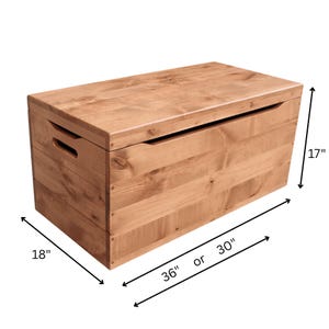 May include: A light brown wooden storage chest with a rectangular shape. The chest is 30 inches long, 18 inches wide, and 17 inches high. It has a hinged lid and cut-out handles on the sides.