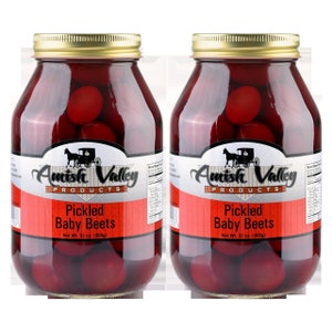 May include: Two glass jars of Amish Valley Pickled Baby Beets. Each jar has a gold lid and a label with the brand name, a horse-drawn carriage illustration, and the text "Pickled Baby Beets, Net Wt. 32 oz. (908g)".