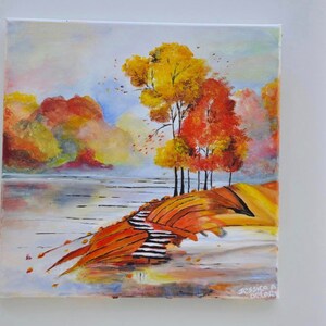 May include: A painting of a fall landscape with a lake, trees, and a path leading up a hill. The trees are painted in shades of yellow, orange, and red. The lake is a light blue color. The path is a light brown color. The painting is signed "Jessica A. Delord".