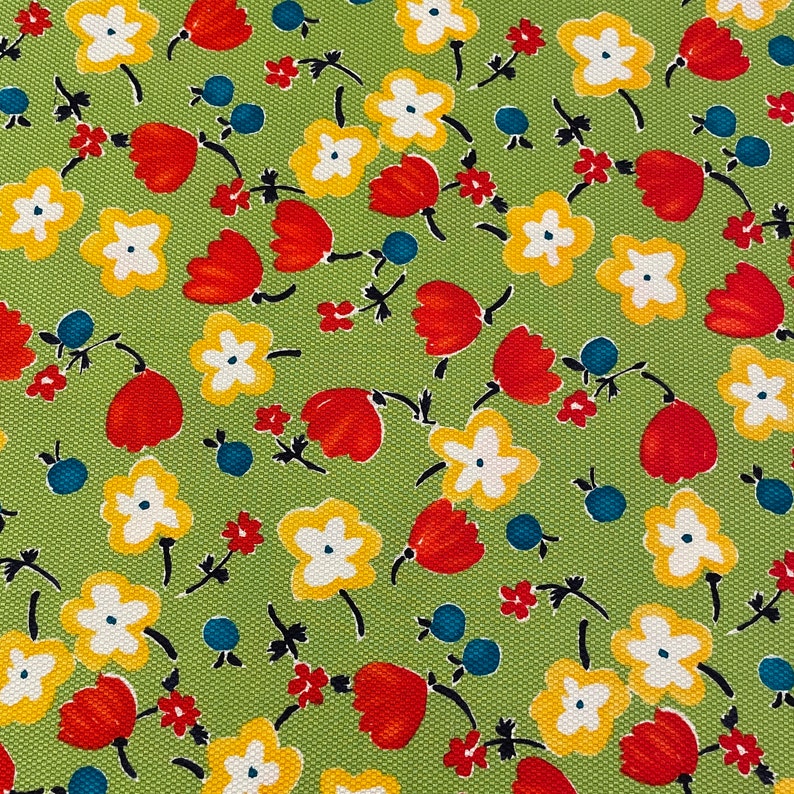 May include: A green fabric with a repeating pattern of red, yellow, and white flowers. The flowers are stylized and have a simple design.
