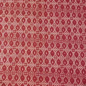May include: Red fabric with a white geometric pattern. The pattern features a repeating design of squares and diamonds with small leaf-like shapes.