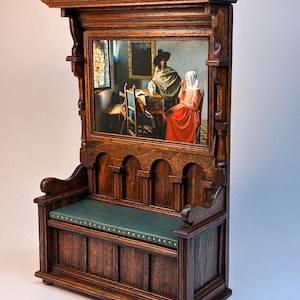 May include: A miniature wooden hall bench featuring a framed painting. The bench is crafted from dark stained wood and has a dark green leather seat. The painting within the frame depicts two figures in a room with a window.