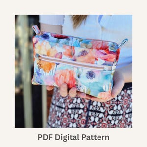 Pode incluir: Uma clutch com estampa floral com um design em aquarela com flores laranja, rosa e azul. A clutch tem um zíper dourado e uma pequena argola em cada lado. O texto "PDF Digital Pattern" está na parte inferior da imagem.