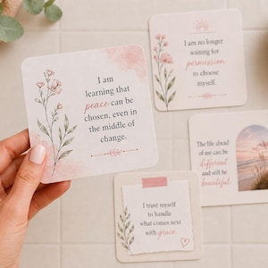 Può includere: Una mano tiene in mano una carta quadrata con il testo "Sto imparando che la pace può essere scelta, anche nel mezzo del cambiamento". Sono visibili altre carte con disegni floreali e citazioni ispiratrici.
