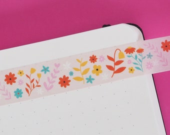 Könnte beinhalten: Ein weißes Notizbuch mit einem rosa floralen Washi-Tape-Rand. Das Notizbuch hat ein gepunktetes Rastermuster.