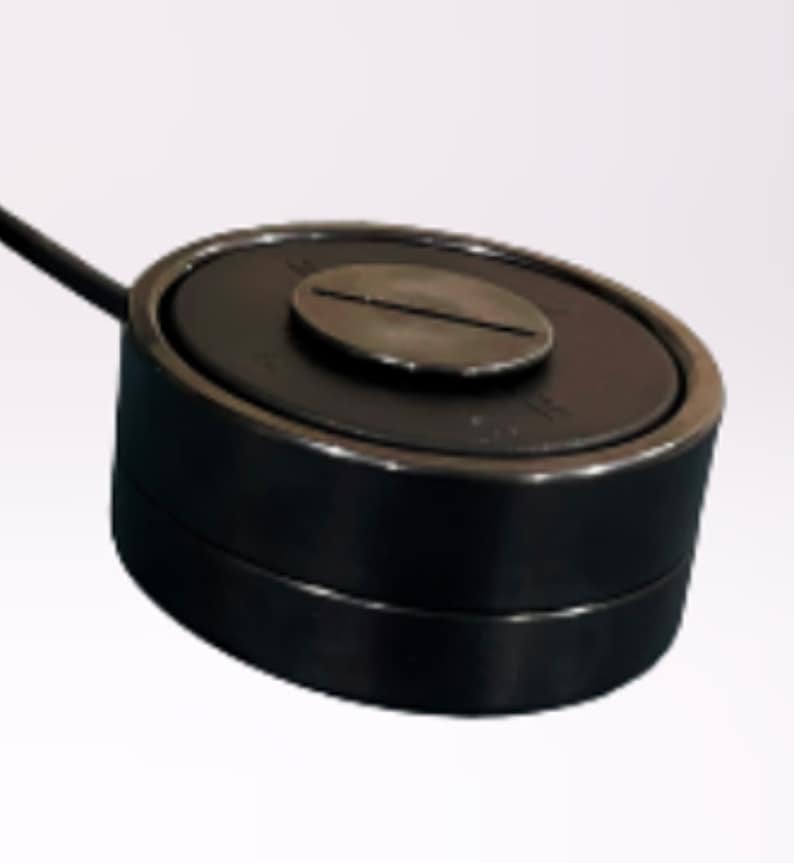 May include: A black round electronic device with a silver screw on top. The device has a black cord attached to it.
