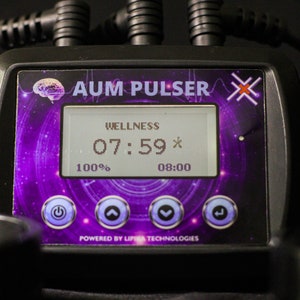 May include: A black device with a purple and white screen displaying "WELLNESS 07:59* 100% 08:00" and the text "AUM PULSER X" above the screen. The device has four buttons: power, up arrow, down arrow, and a right arrow.