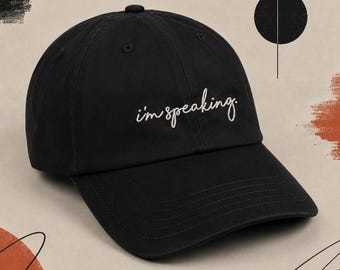 May include: Black baseball cap with the embroidered phrase "i'm speaking" in white script. The cap has a curved brim and a rounded crown. The hat is a classic style, suitable for casual wear.