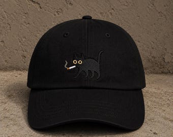 May include: Black baseball cap featuring an embroidered black cat smoking a cigarette. The cat has yellow eyes and is walking. The cap has a curved brim and a button on top. The background is a textured, neutral color.