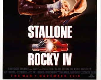 Puede incluir: Un póster de película para la película "Rocky IV" protagonizada por Sylvester Stallone. El póster presenta un primer plano de Stallone, sin camisa, envolviendo sus manos con cinta de boxeo. El título "Stallone Rocky IV" se muestra en letras grandes y en negrita. El lema "The War - November 27th" se muestra en la parte inferior del póster.