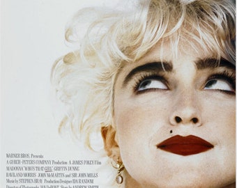 May include: A movie poster for the film "Who's That Girl" starring Madonna. The poster features a close-up of Madonna's face, with her signature blonde hair and bold makeup. The title of the film is written in large, white letters at the top of the poster.