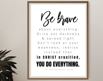 May include: Black and white inspirational quote print with a wooden frame. The quote reads "Be brave about everything. Drive out darkness & spread light. Don't look at your weakness, realize instead that in CHRIST crucified, YOU DO EVERYTHING. ST. CATHERINE OF SIENA"