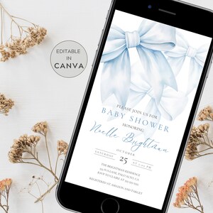 May include: A blue and white baby shower invitation with a watercolour bow design. The invitation text reads "Please join us for Baby Shower honouring Noelle Brighton Saturday October 25 at 1:00 PM The Brightman Residence 50 Iva Lane, Palo Alto, CA RSVP to Claire at 555-555-5555 Registered at Amazon and Target"