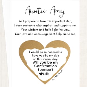 May include: A white card with gold lettering that says "Auntie Amy" and a gold heart with a scratch-off area that says "Will you be my Confirmation Sponsor? Bella".