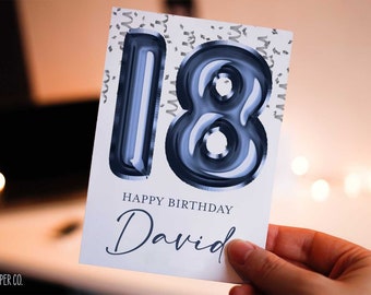 May include: A white card with a blue number 18 made of balloons. The card says "Happy Birthday David" in black text.
