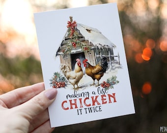 May include: A greeting card with a watercolor illustration of two roosters in front of a snow-covered wooden shed. The text "making a list CHICKEN IT TWICE" is printed in red and black. The card has a festive, winter theme.