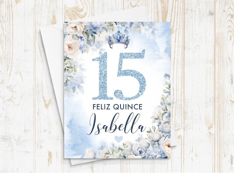 May include: A blue and white quincea&ntilde;era invitation with a sparkly blue number 15, a crown, and the text "Feliz Quince Isabella".