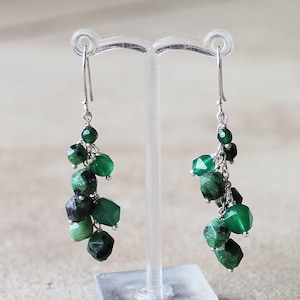May include: Silver dangle earrings with a cluster of green gemstone beads.