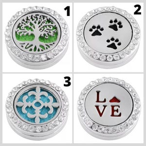 May include: Four silver aromatherapy essential oil diffuser lockets with different designs. One has a tree of life, another has paw prints, a third has a snowflake design, and the last one says "LOVE". Each locket is surrounded by clear crystals.