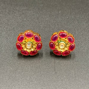Può includere: Un paio di orecchini a bottone in oro con un design floreale. Gli orecchini sono adornati con pietre preziose rosse e verdi.
