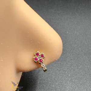 Op de afbeelding: Gouden neusring met een bloemmotief met roze en witte stenen.
